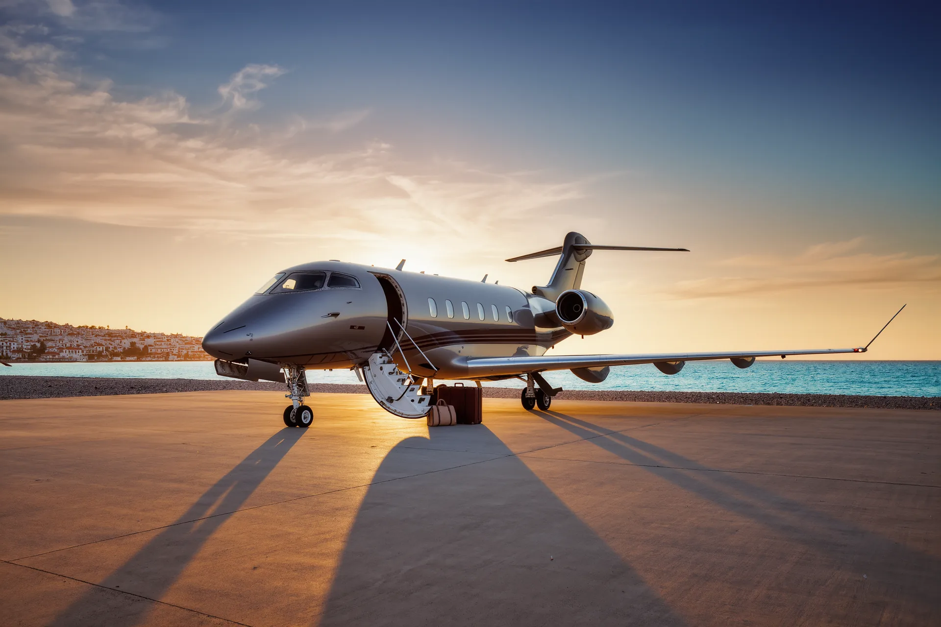 Jet privado estacionado en la pista al atardecer con la escalerilla desplegada y una silueta de equipaje junto a la puerta