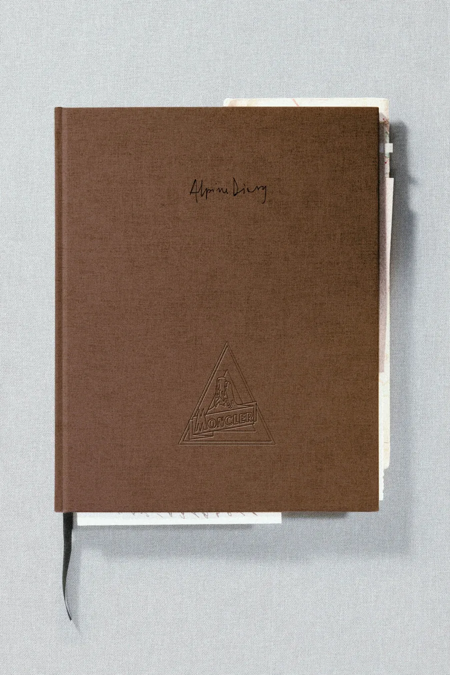 Moncler Alpine Diary: libro con tapa de tela marrón y un motivo de montaña grabado