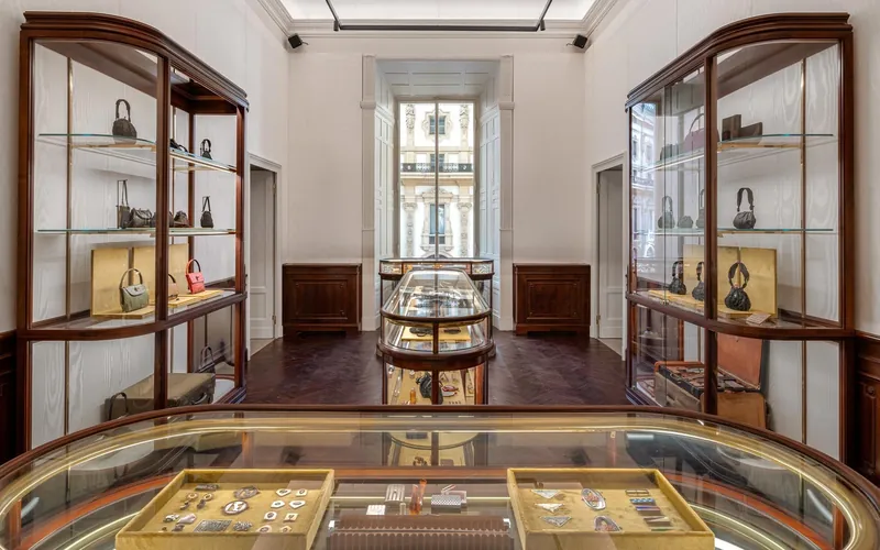 Prada Galleria en Milán: sala con vitrinas de madera llenas de bolsos y una vitrina ovalada de cristal con piezas de archivo