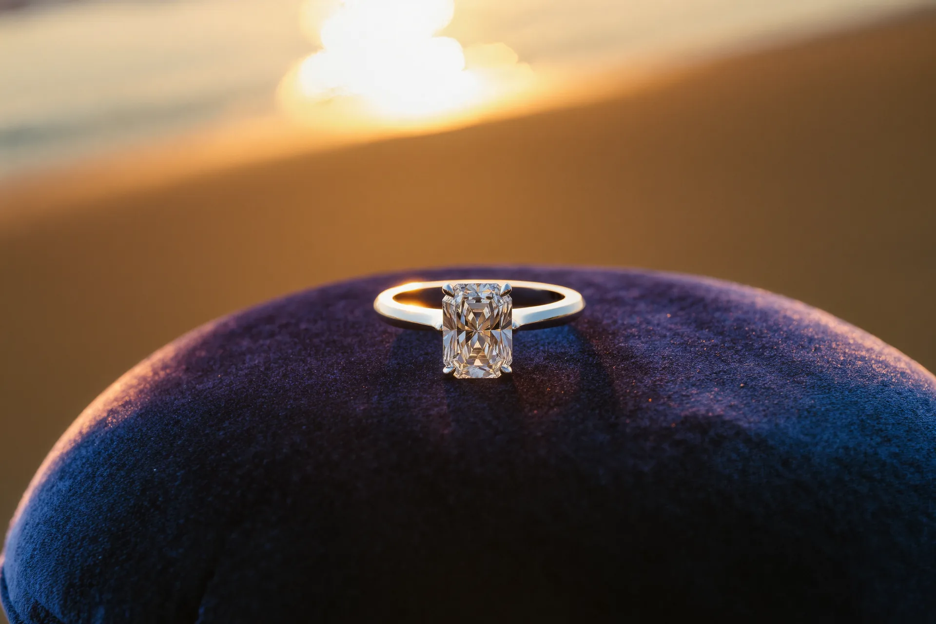 Anillo de compromiso con diamante solitario fotografiado sobre terciopelo oscuro con luz cenital