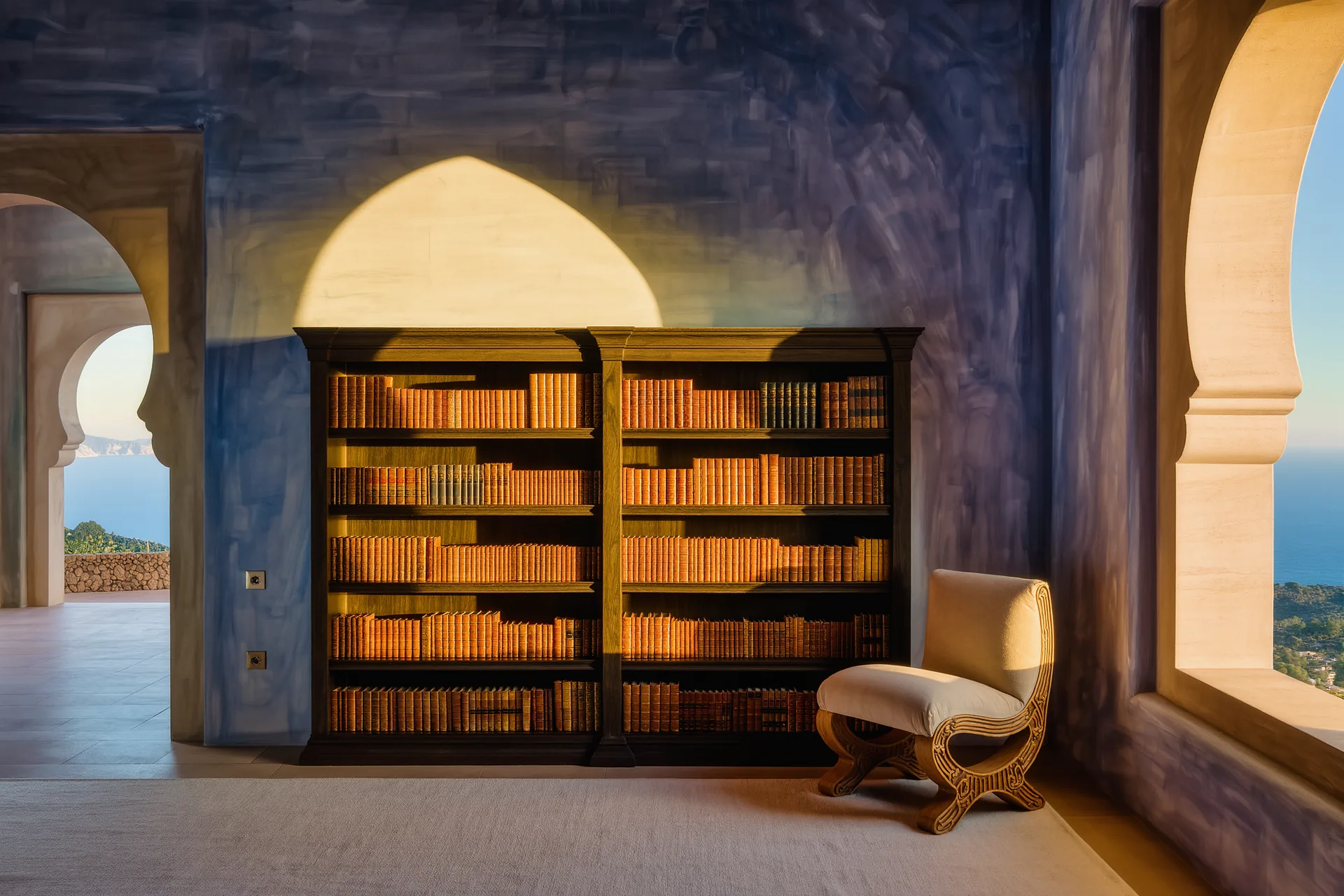 Estantería de madera oscura repleta de libros de distintos lomos junto a un sillón de lectura iluminado por luz natural