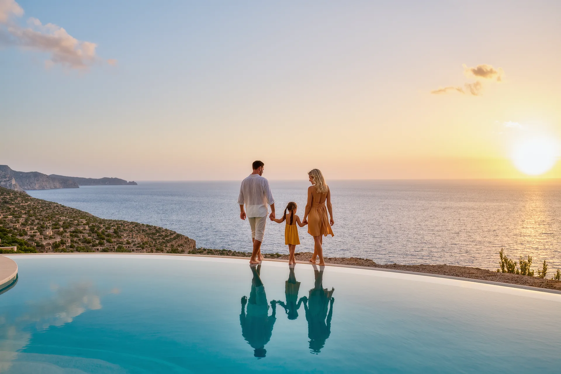 Familia caminando descalza por la orilla de una piscina infinita frente al mar al atardecer, en un resort de lujo